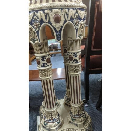 248 - A late 19th century earthenware jardiniere stand supported by four columns glassed in a polychrome e... 