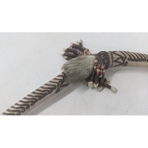 57 - A tribal weapon having heavily carved bone handle and animal skin with beaded tassel decoration
Loca... 