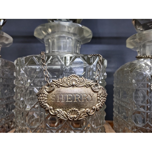 338 - An early 20th century oak Tantalus with three cut crystal decanters and silver plated decanter label... 