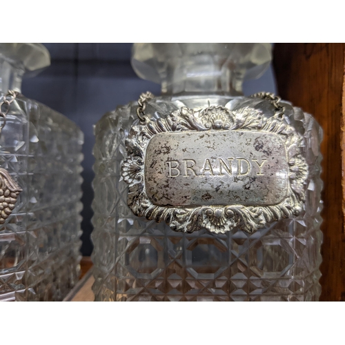 338 - An early 20th century oak Tantalus with three cut crystal decanters and silver plated decanter label... 