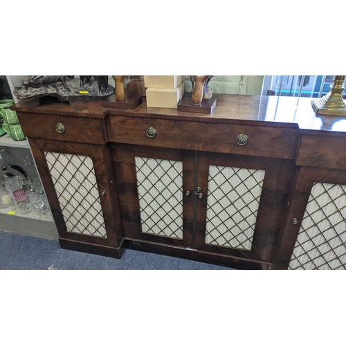 357 - A Regency mahogany break front sideboard having three drawers above four doors with pierced grille f... 