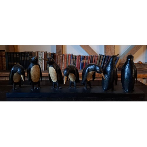 198 - A black and cream metal display of 7 penguins. in various positions, approx 80cm wide x 26cm high Lo... 