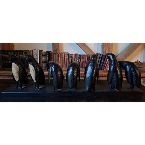 198 - A black and cream metal display of 7 penguins. in various positions, approx 80cm wide x 26cm high Lo... 