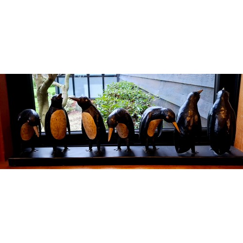 198 - A black and cream metal display of 7 penguins. in various positions, approx 80cm wide x 26cm high Lo... 