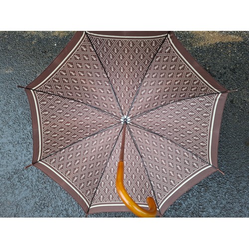 16 - YSL- A mid 20th Century brown and cream branded umbrella having a cane handle. Location:
If there is... 