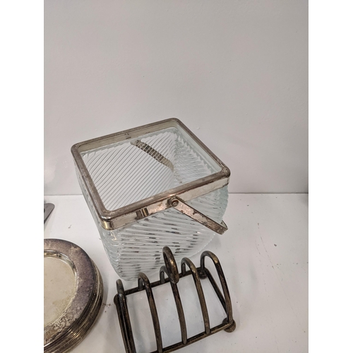 181 - A collection of silver plated items to include a glass basket, two toast racks, a napkin holder, nap... 