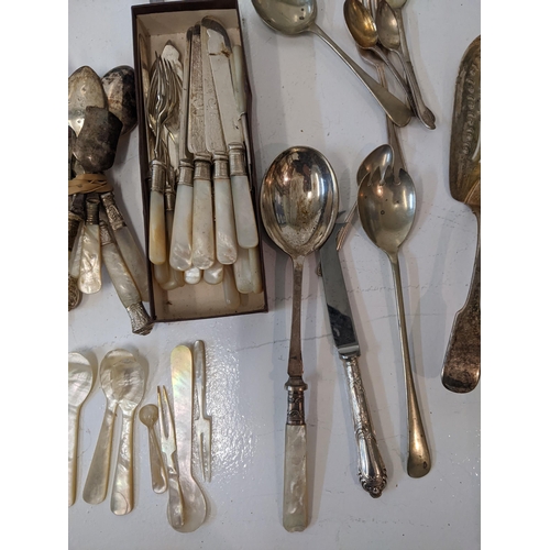 183 - A collection of silver plated flatware to include two pairs of tongs, a fish slice along with mother... 