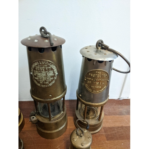 239 - A collection of seven miner's lamps to include The Protector Type 1A, another similar and reproducti... 