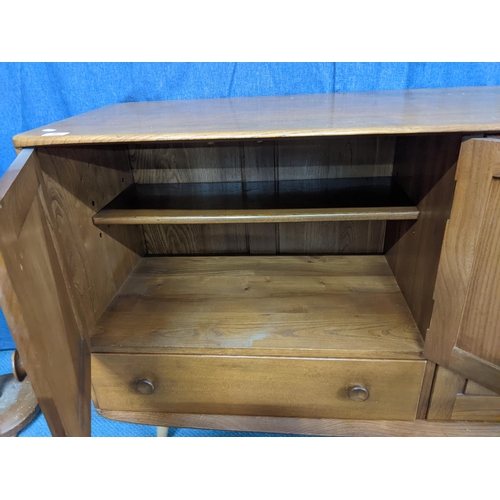 262 - A mid century blonde Ercol sideboard with two small panelled cupboards over a long drawer and one la... 