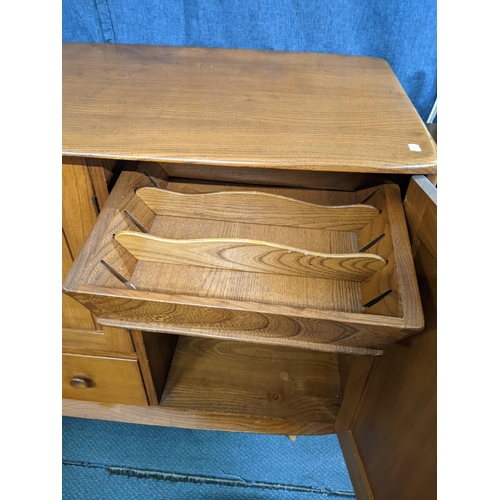 262 - A mid century blonde Ercol sideboard with two small panelled cupboards over a long drawer and one la... 