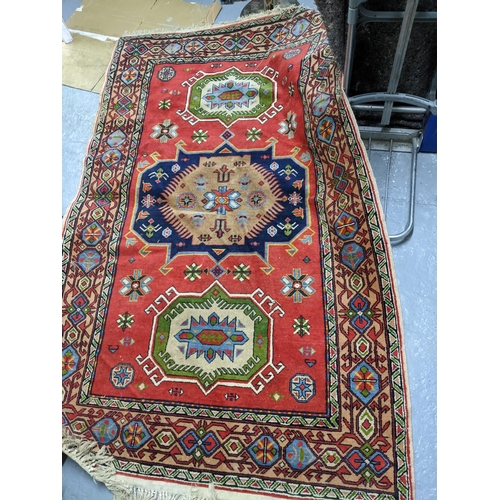 328 - A vintage hand woven Afghan style rug, three elephant gulls on a red ground, stylized floral motifs,... 