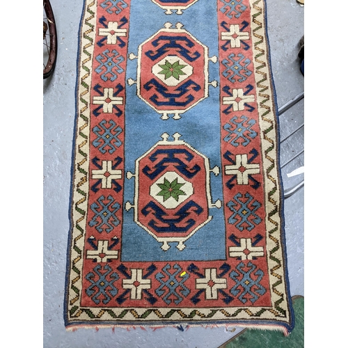 329 - A hand woven Turkish style runner, five central floral medallions on a sky blue ground, double guard... 