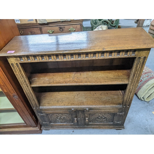 347 - A 20th century carved oak bookcase/side cupboard of small proportions, two open shelves above twin c... 