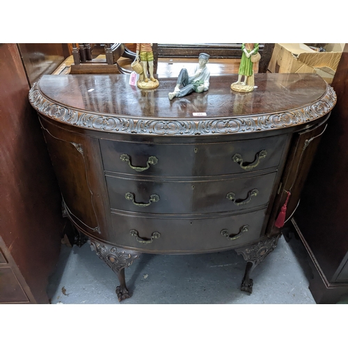 351 - An early 20th century mahogany demi lune side cabinet, top with carved rococo C-scrolls and leaves, ... 