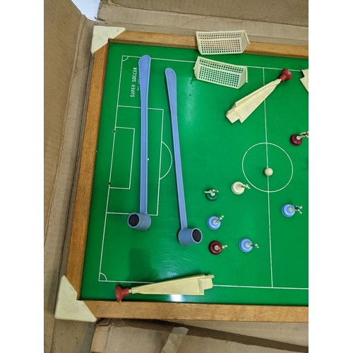 382 - A Super Soccer boardgame consisting of a table  magnetic rods and a quantity of red and blue players... 