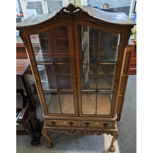 385 - An early 20th century walnut veneered display cabinet, carved rococo leaf design to the arched top, ... 