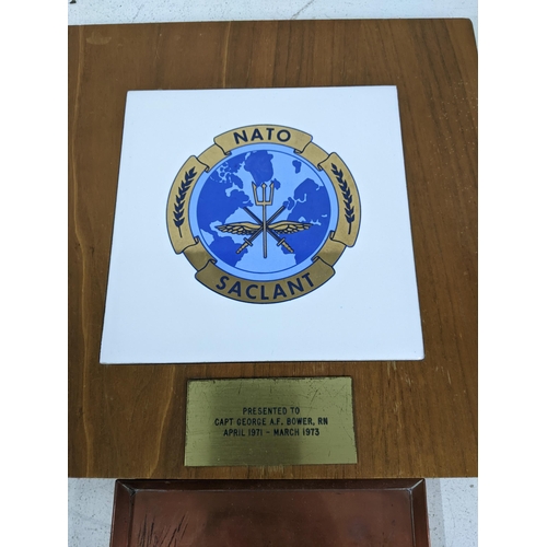 507 - Military related to include a Nato saclant tile inset with a wooden panel, with a plaque to Capt Geo... 