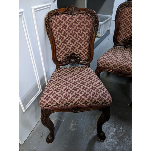 561 - A set of four Victorian rosewood dining chairs with upholstered backs and seats, carved leaf decorat... 