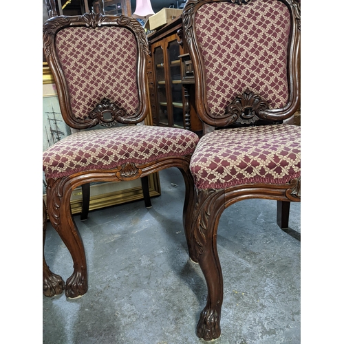 561 - A set of four Victorian rosewood dining chairs with upholstered backs and seats, carved leaf decorat... 