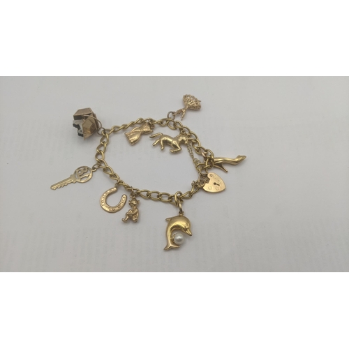 82 - A 9ct yellow gold charm bracelet with 9ct yellow gold charms to include a charm fashioned as a cat, ... 