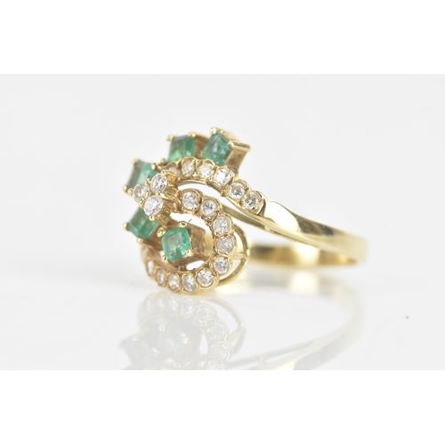 216 - An emerald and diamond 18ct yellow gold dress ring, of scroll design, with five emeralds in claw set... 