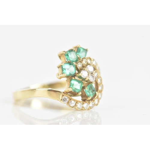 216 - An emerald and diamond 18ct yellow gold dress ring, of scroll design, with five emeralds in claw set... 