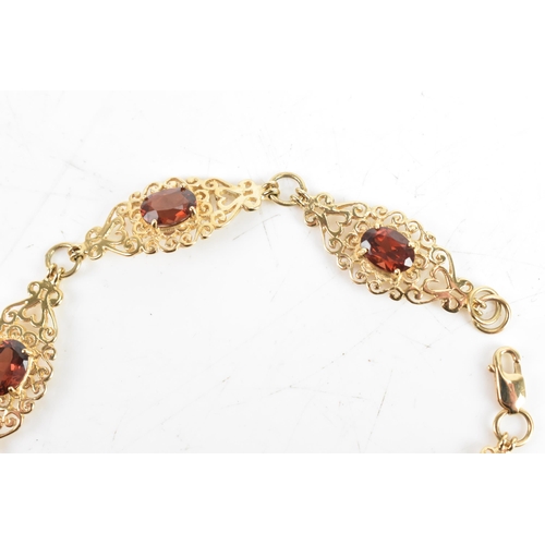 219 - A garnet 9ct gold bracelet, having six filigree panels with heart and scrolls, each inset with oval ... 