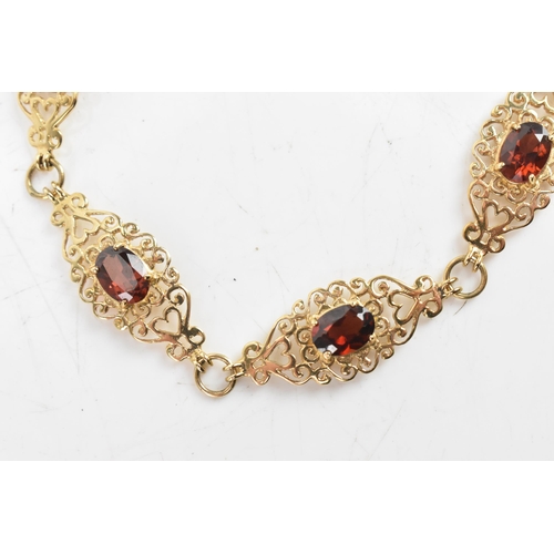 219 - A garnet 9ct gold bracelet, having six filigree panels with heart and scrolls, each inset with oval ... 