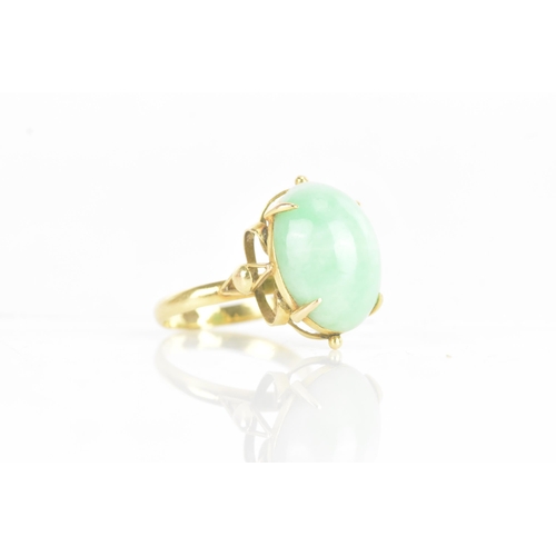 223 - A Chinese jadeite yellow gold dress ring, the oval jadeite cabochon 17.2mm x 12.8mm, in a four claw ... 