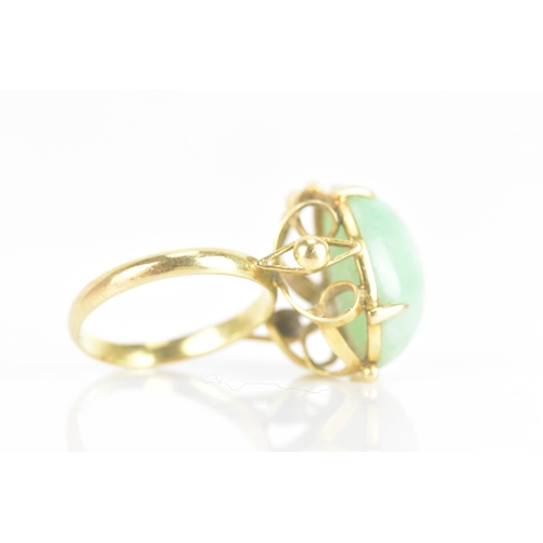 223 - A Chinese jadeite yellow gold dress ring, the oval jadeite cabochon 17.2mm x 12.8mm, in a four claw ... 