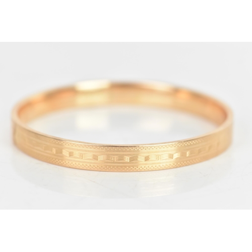 24 - A 1920s 15ct gold bangle, having engine turned decoration with bands of geometric designs, hallmarke... 