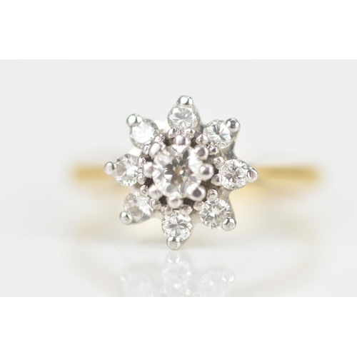 28 - A diamond 18ct yellow gold cluster daisy ring, the central brilliant cut diamond 3.5mm diameter, in ... 