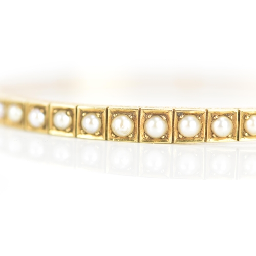 3 - A Victorian 15ct gold bangle, inset with thirteen pearls in claw settings, the gallery engraved with... 