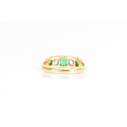 43 - A Victorian emerald and diamond 18ct yellow gold ring, having three emeralds flanking two old cut di... 