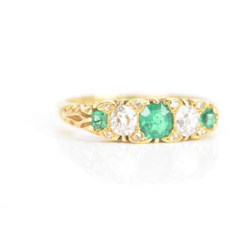 43 - A Victorian emerald and diamond 18ct yellow gold ring, having three emeralds flanking two old cut di... 