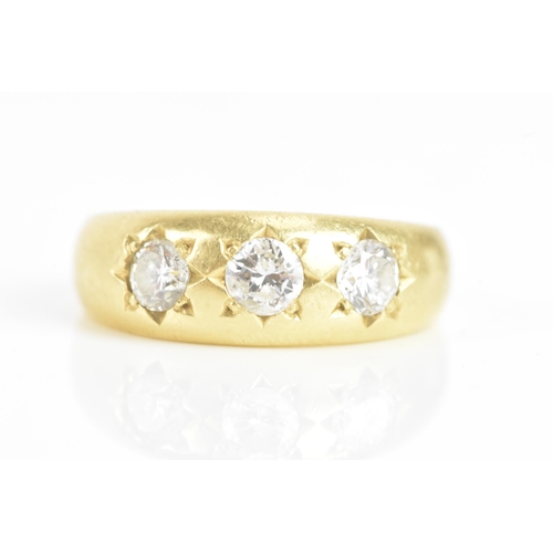 57 - A diamond 18ct yellow gold gypsy ring, having three brilliant cut diamonds in claw settings, the cen... 