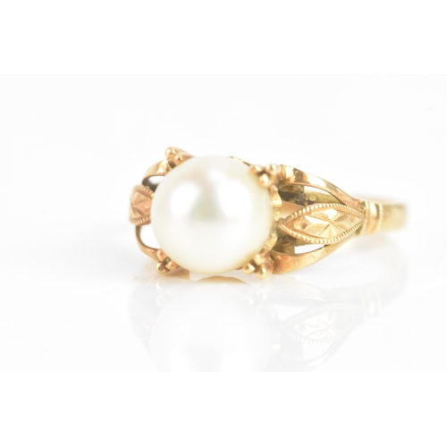 59 - A pearl 18ct yellow gold dress ring, the central pearl 7.8mm, in a four prong setting, with pierced ... 