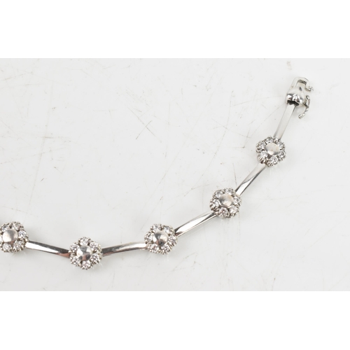 66 - A diamond 9ct white gold bracelet, the flexible links connected to flower ten flower heads, each ins... 