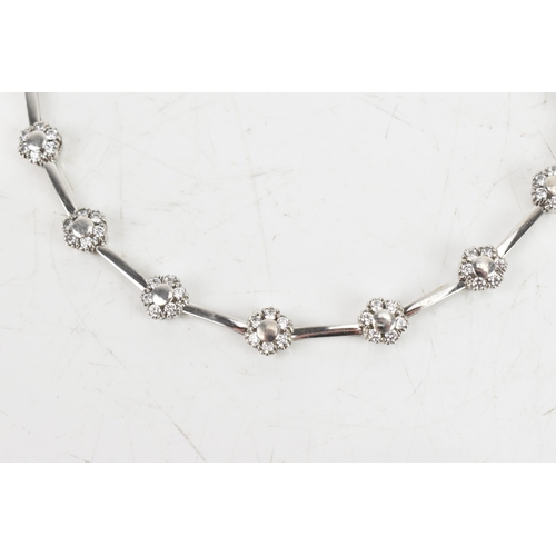 66 - A diamond 9ct white gold bracelet, the flexible links connected to flower ten flower heads, each ins... 