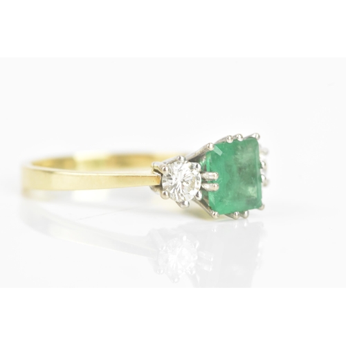 72 - An emerald and diamond 18ct yellow and white gold ring, the central emerald 6.3mm x 5.4mm, flanked b... 