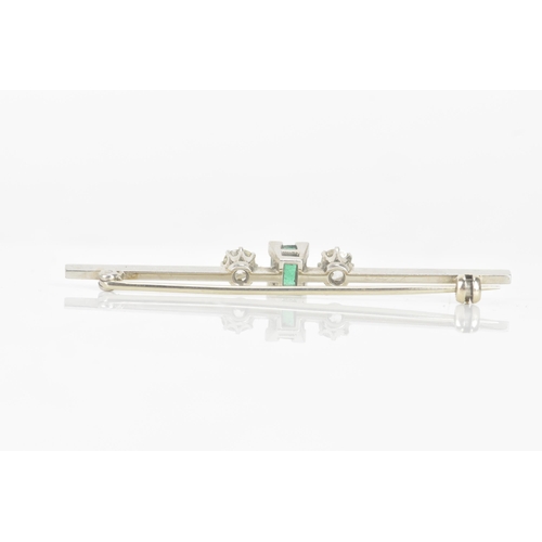 260 - An early 20th century emerald and diamond white metal bar brooch, the central emerald measuring 5.3m... 