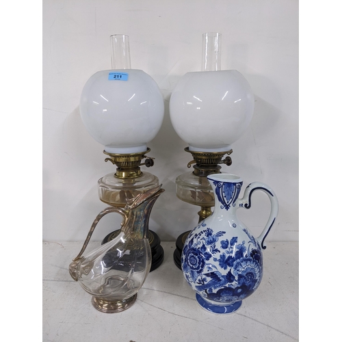 211 - A pair of oil lamps with clear reservoirs and white  glass shades, along with a silver plated decant... 