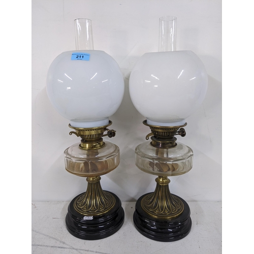 211 - A pair of oil lamps with clear reservoirs and white  glass shades, along with a silver plated decant... 