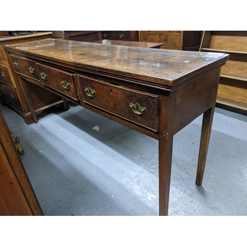 468 - A Georgian oak dresser base, three frieze drawers with brass swan neck handles on square tapering le... 