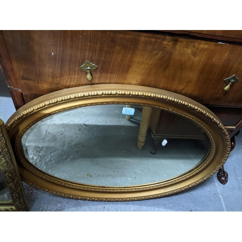 484 - Two gilt framed wall mirrors, an oval mirror, and an overmantel mirror with leaf and berry decoratio... 