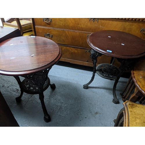 485 - Two cast iron and mahogany topped pub tables, the circular tops with moulded edge, the black painted... 