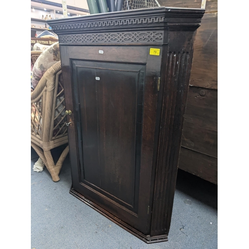 73 - A late 19th/early 20th century hanging oak corner cupboard with an ornate frieze, panelled door and ... 