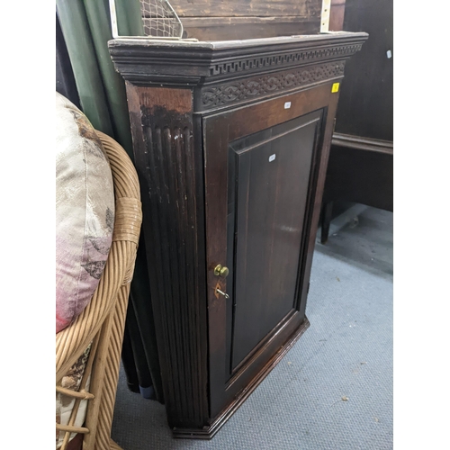 73 - A late 19th/early 20th century hanging oak corner cupboard with an ornate frieze, panelled door and ... 