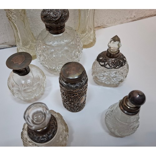 59 - A collection of 8 glass perfume bottles to include examples with silver and white metal collars and ... 