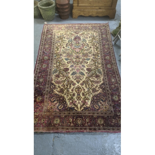 583 - A handwoven Persian silk rug on beige ground and red border decorated with flowers in a vase, surrou... 